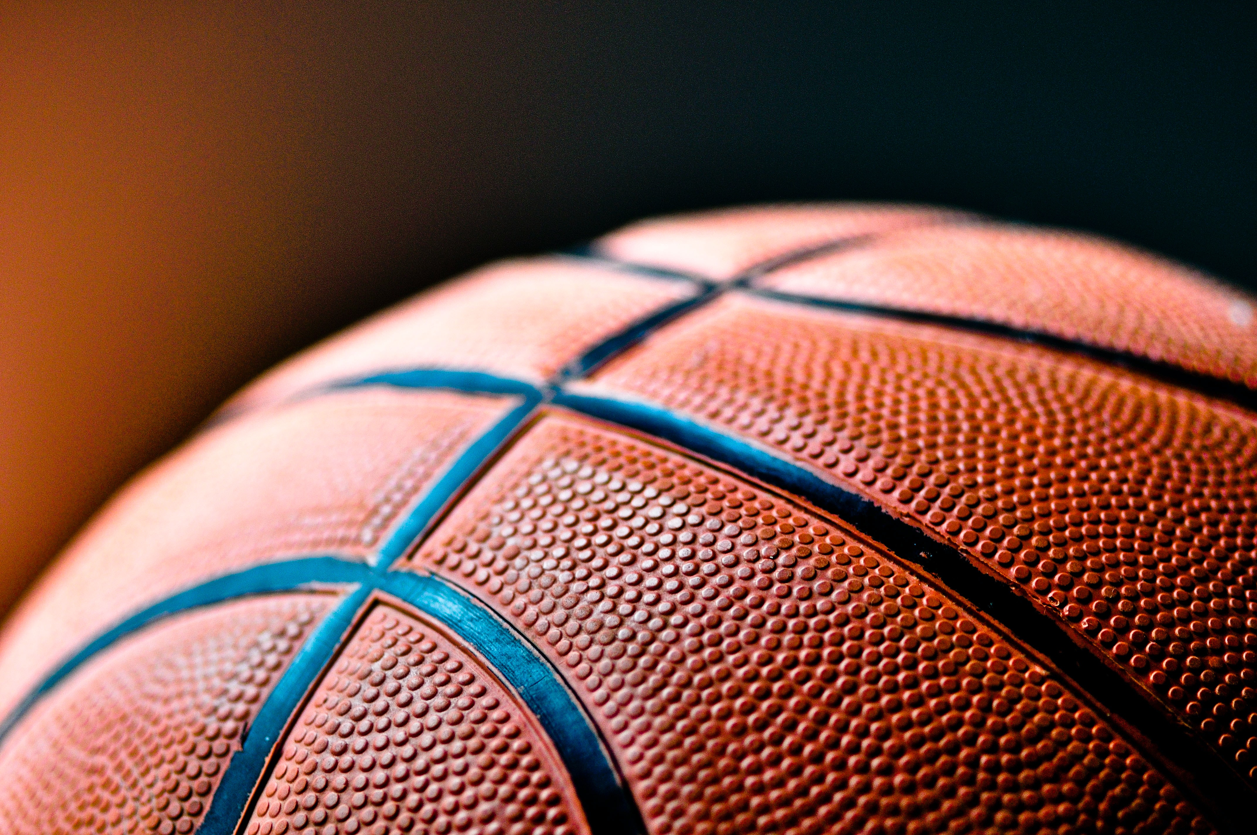 Three quarters of a basketball against a orange to brown gradient background.