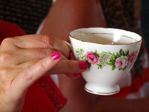 Person holding a tea cup with pinkie extended up