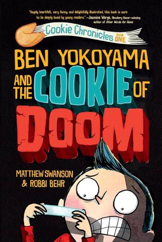 The cover of the book, "Ben Yokoyama and the Cookie of Doom" depicts an illustrated young boy with black hair, and large round eyes, staring in terror at the fortune from a fortune cookie.
